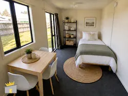Cabin King: A large cabin furnished with a bed and a bookshelf, showing how a cabin can be used as a guest room or sleepout.